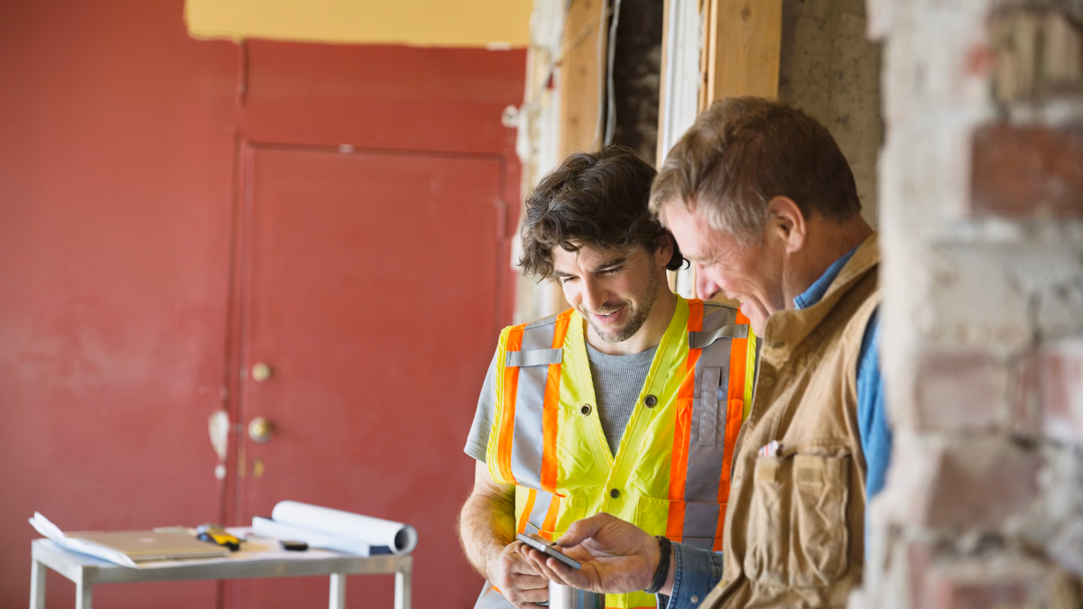 Tradesman talking to a customer on site, the smartphone recording the appointment